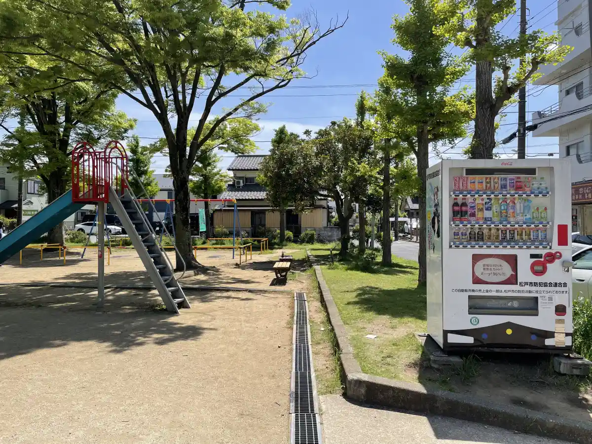 滑り台とブランコ、自動販売機が見える広田公園の遊具エリア